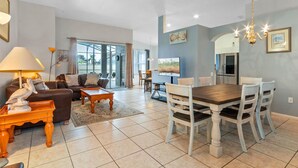 A spacious living area with a dining table and chairs, a sofa, a coffee table, and a TV. - 3Br 2Ba Private Pool Villa Just Steps Away From (Kissimmee)