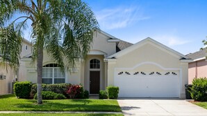 A residential house with a white garage, a front door, and a well-maintained lawn. - 4 Bedroom 3 Bath South Facing Pool Spa Villa (Kissimmee)