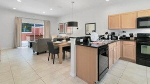 A modern kitchen with a dining area, wooden cabinets, and a large island. - Amazing Townhouse Close to Disney 2 Bed 2 5 Bath (Kissimmee)