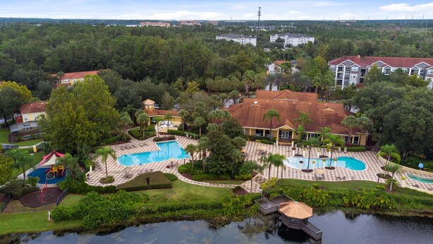 A resort with multiple swimming pools, a large lawn, and a lake. - Amazing Townhouse Close to Disney 2 Bed 2 5 Bath (Kissimmee)