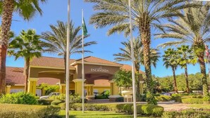 Un hotel llamado "Encantada" con techo de tejas rojas, palmeras y un jardín bien cuidado.