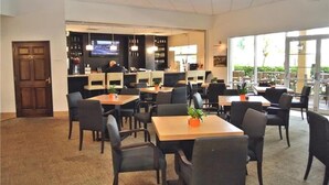 Un restaurante con varias mesas y sillas, una zona de bar y una pantalla de televisión.