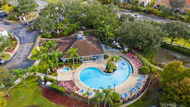 An aerial view of a resort with a large swimming pool, lounge chairs, and palm trees. - Lucaya Village Resort - 4 Bed 3 Bath Townhouse (Kissimmee)