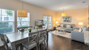 A spacious living room with a dining area, a sofa set, and a television. - Lucaya Village Resort - 4 Bed 3 Bath Townhouse (Kissimmee)