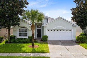 A single-story house with a garage, a front lawn, and a palm tree.