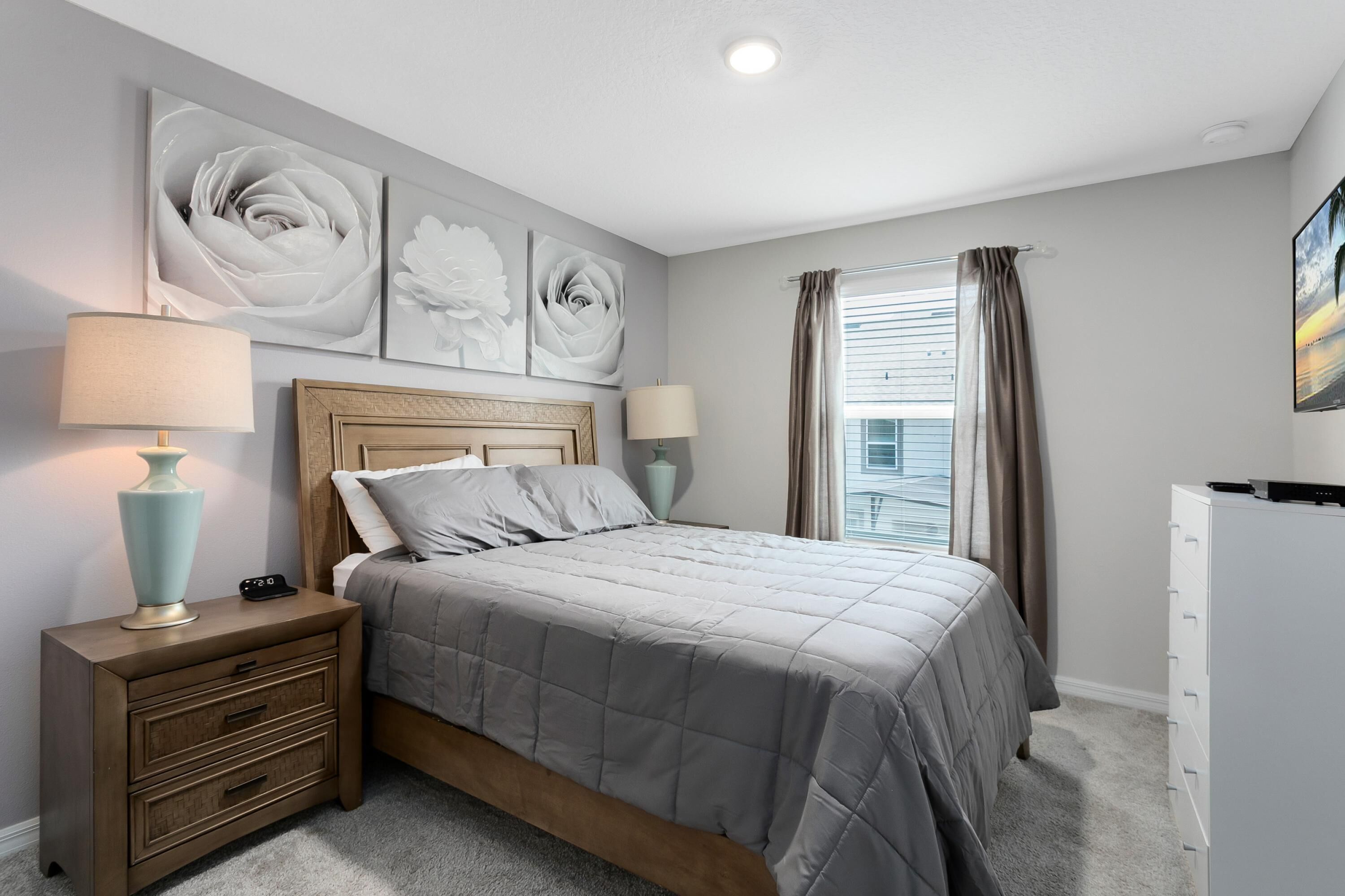 A bedroom with a bed, nightstands, a dresser, and artwork on the walls.