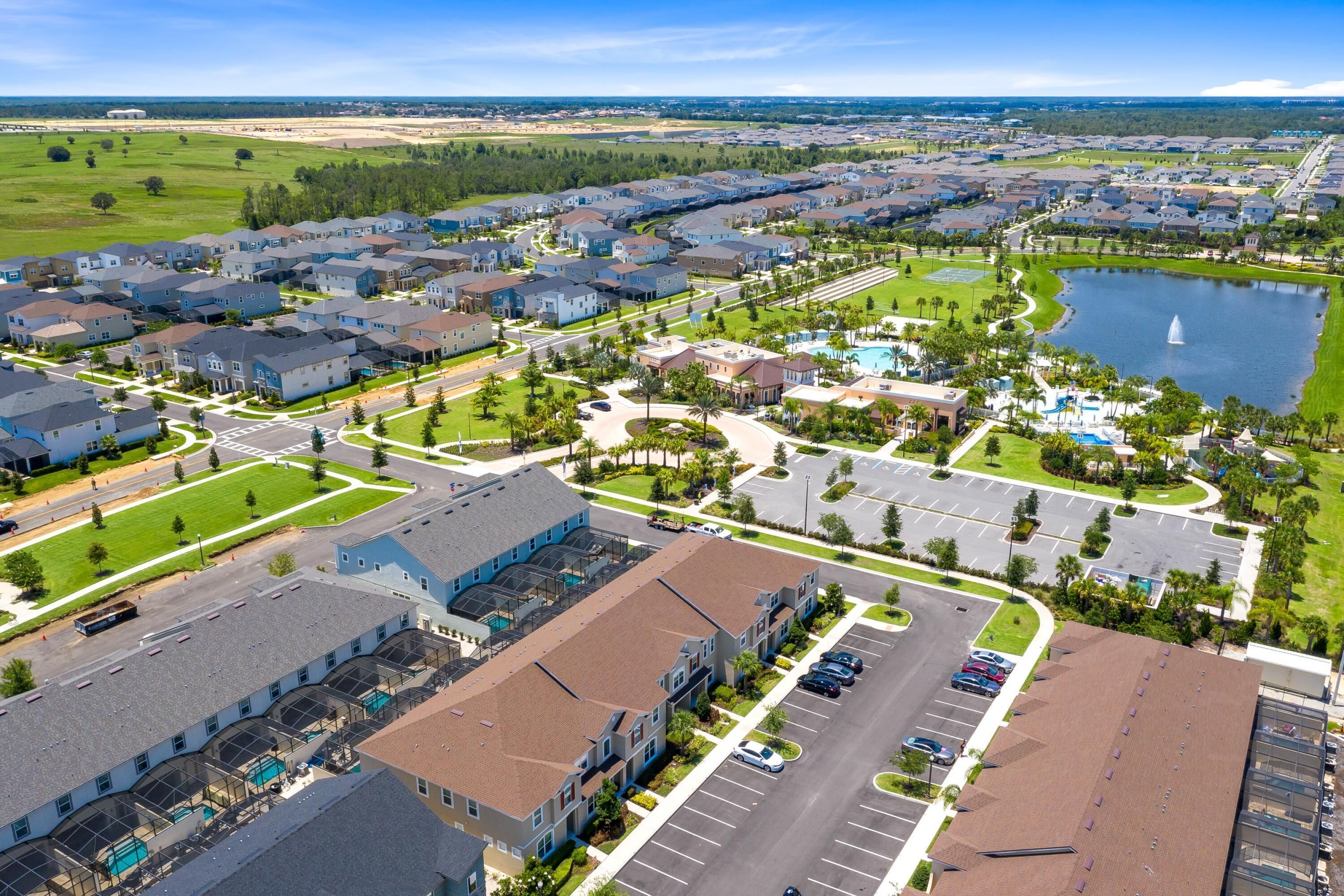 An aerial view of a residential area with houses, a parking lot, and a lake.