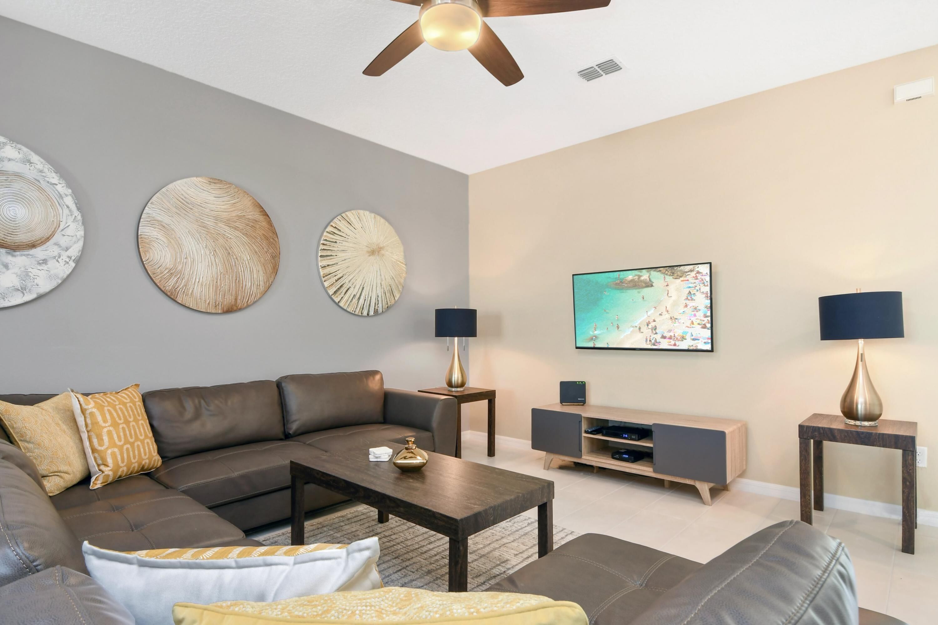 A modern living room with a sectional sofa, a coffee table, a TV, and two side tables with lamps.