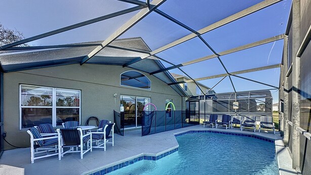 A swimming pool with lounge chairs and a covered patio area.