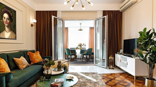 A living room with a sofa, coffee table, TV, and a dining area with chairs and a table. - Qult·co - The Renaissance Affair (București)