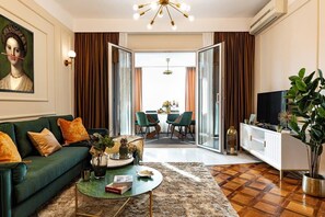 A living room with a sofa, coffee table, TV, and a dining area with chairs and a table. - Qult • The Renaissance Affair (București)