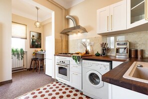 A kitchen with a built-in oven, a washing machine, a coffee machine, and a sink. - Qult • The Renaissance Affair (București)