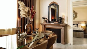 A dining area with a glass table, chairs, a vase with dried flowers, a fireplace, and a mirror. - Qult·co - The Aristocrat (București)