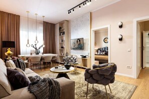 A modern living room with a sofa, armchair, dining table, and decorative items. - Qult·co - Dune (București)