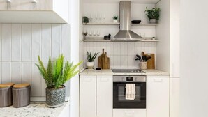 Une cuisine moderne avec des meubles blancs, une hotte en acier inoxydable et un four encastré.