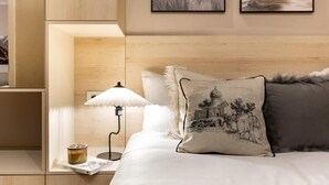 Une chambre bien rangée, avec un lit, une table de chevet dotée d’une lampe et une petite table de nuit.