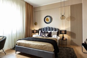 A modern bedroom with a large bed, two bedside lamps, a decorative wall piece, and a view of the outside through sheer curtains.