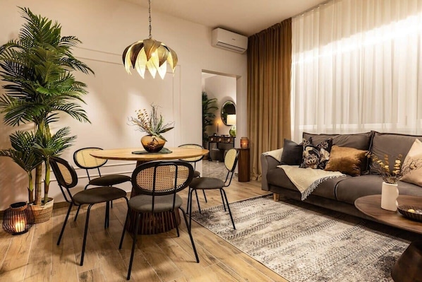 A modern living room with a dining area, a sofa, and a large potted plant.