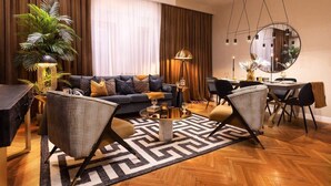 Un salon moderne comprenant un canapé, deux fauteuils, une table basse, une table à manger avec des chaises, un grand miroir et une plante en pot.