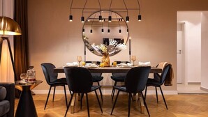 Un coin repas avec une table ronde, des chaises noires, un vase central et un miroir au-dessus.