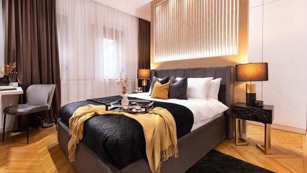 Une chambre d’hôtel moderne, dotée d’un grand lit, de tables de chevet, d’un bureau et d’une chaise.