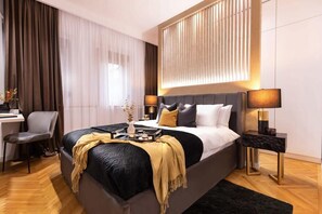 A modern hotel room with a large bed, bedside tables, a desk, and a chair.