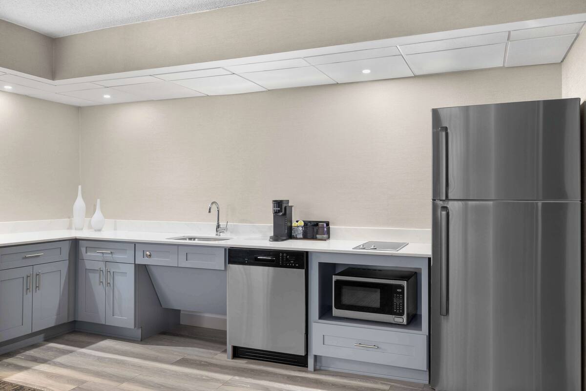 Eine moderne Küche mit grauen Schränken, einem Edelstahl-Kühlschrank, einem Geschirrspüler und einem eingebauten Backofen.