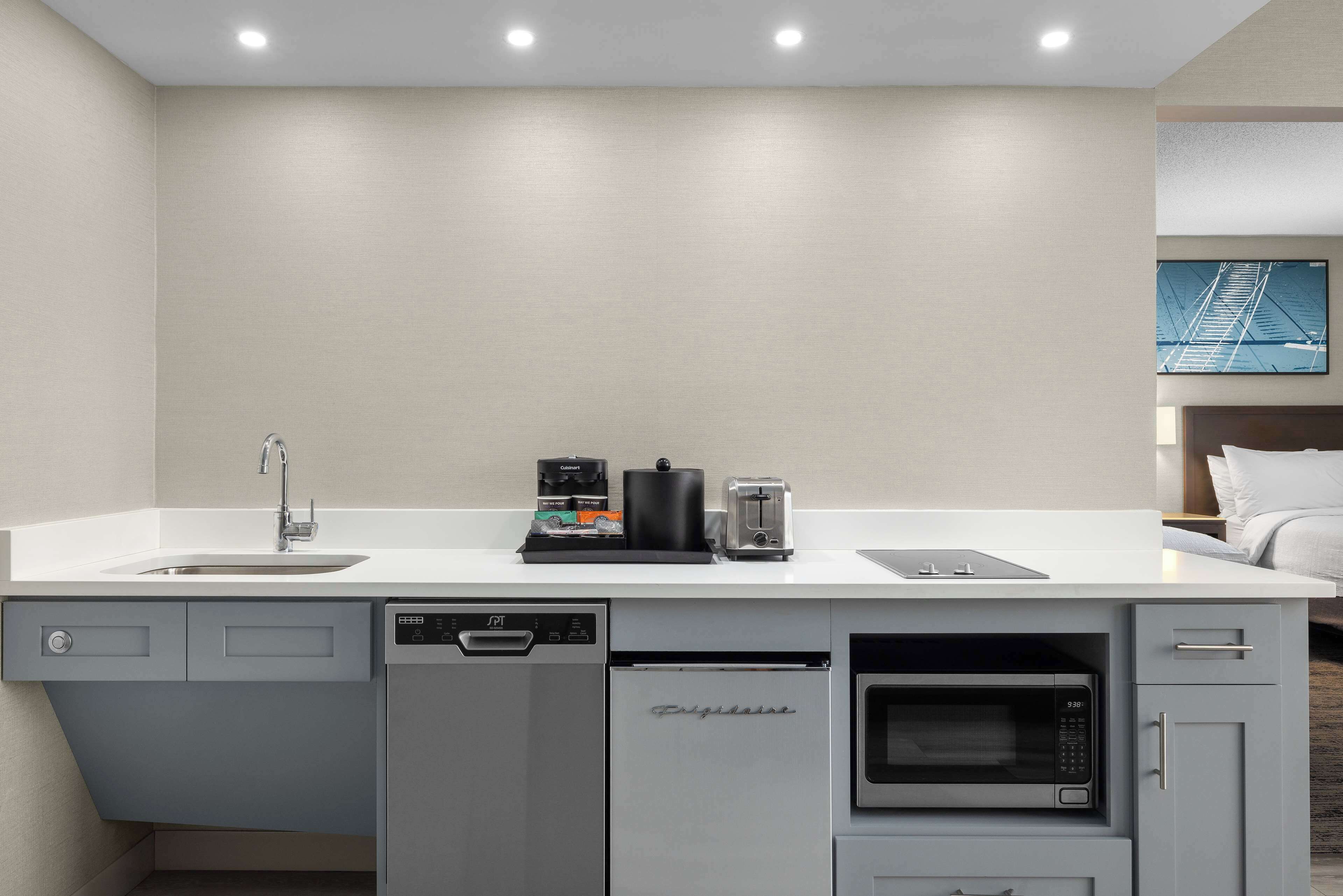 A modern kitchen with a dishwasher, a coffee maker, a toaster, and a microwave.