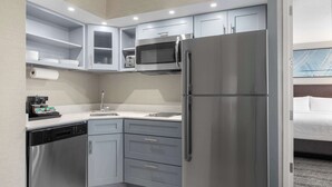 A compact kitchen with a stainless steel refrigerator, a microwave, and a dishwasher.