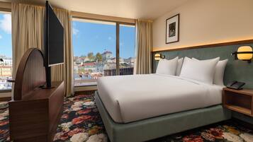 Une chambre d’hôtel avec un grand lit, une télévision, un bureau et une vue sur la ville.
