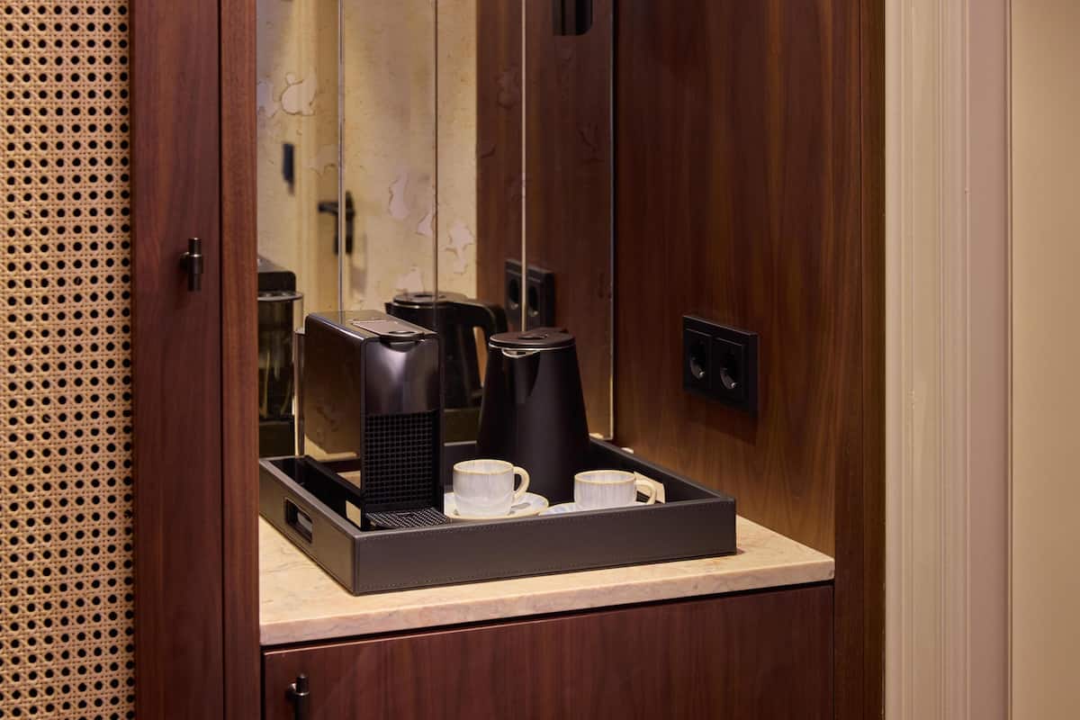 Un mini-bar comprenant une machine à café, deux tasses et un plateau.
