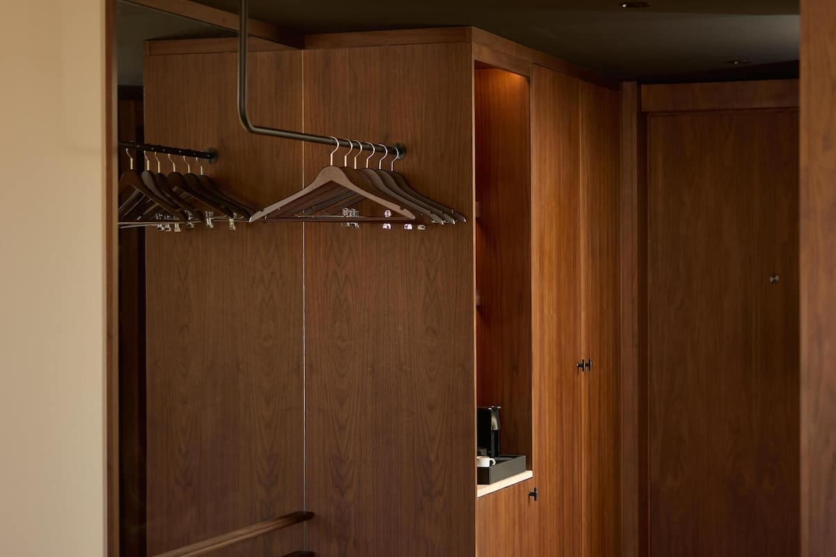 Une chambre à coucher moderne avec une armoire en bois, un lit et un banc.