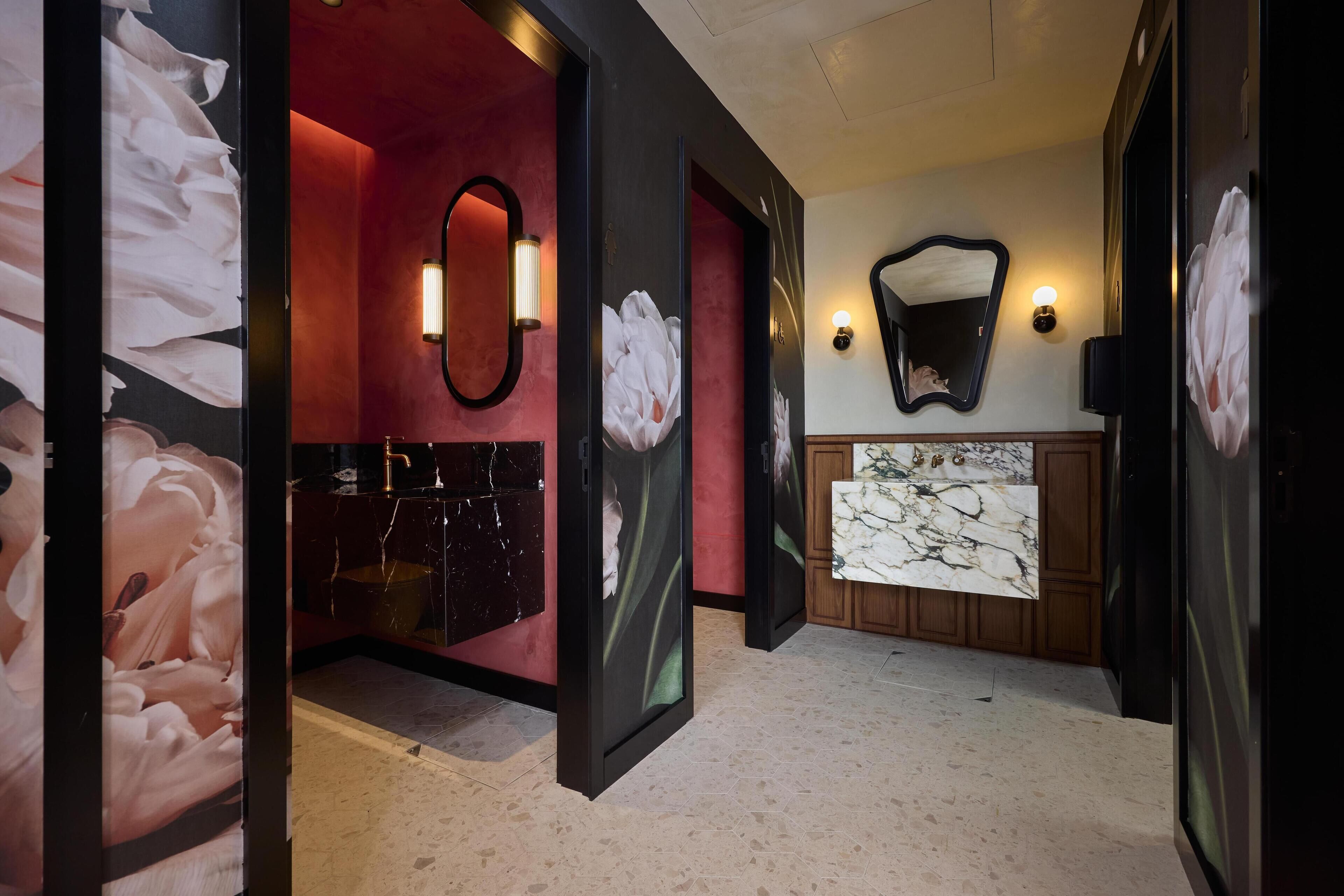A hotel bathroom with a red wall, a marble sink, and a large mirror.
