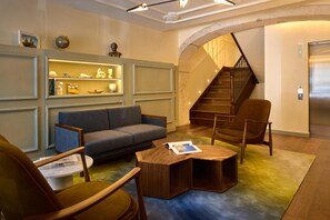 Ein modernes Wohnzimmer mit einer Couch, Sesseln, einem Couchtisch und einer Treppe.