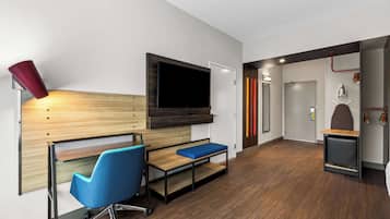 Una habitación moderna con un escritorio de madera, una silla azul y un televisor montado en la pared.