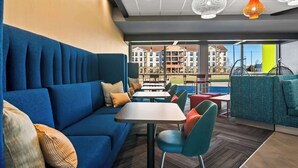 A modern lounge area with a blue sofa, teal chairs, and a wooden table. - Tru By Hilton Rogers Bentonville (Rogers)