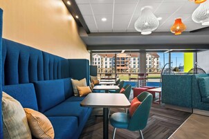 Un área de estar moderna con un sofá azul, sillas color turquesa y una mesa de madera.