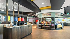 A modern cafe interior with a coffee bar, seating area, and a snack kiosk. - Tru By Hilton Rogers Bentonville (Rogers)