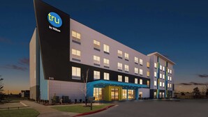 A modern hotel building with a prominent 'tru by Hilton' sign, multiple floors, and a well-lit entrance. - Tru By Hilton Rogers Bentonville (Rogers)