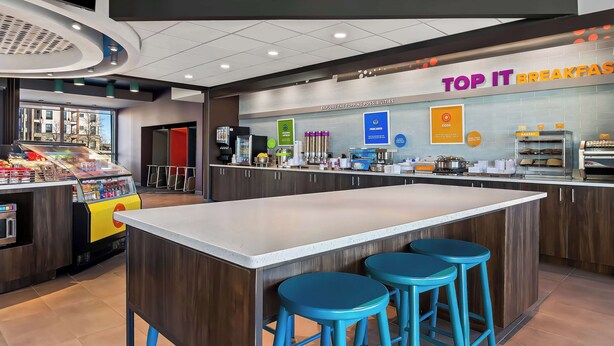 A modern breakfast area with a counter, stools, and a sign reading "TOP IT BREAKFASTS". - Tru By Hilton Rogers Bentonville (Rogers)