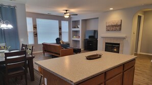 A modern kitchen with a central island, wooden cabinets, and a fireplace. - Kid Friendly Comfy Get Away (Victorville)