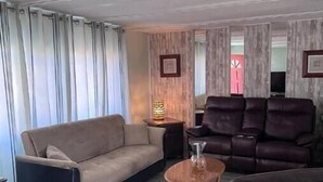 Un salon avec un canapé beige, un canapé en cuir foncé et une table basse.