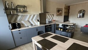 Moderni keittiö, jossa on keskeinen saareke, harmaat kaapit ja kalanruotokuvioinen laattaseinä.