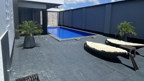 Un espace piscine aménagé sur le toit, avec deux chaises longues et des plantes en pot.