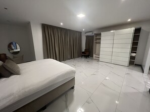 A modern bedroom with a bed, a wardrobe, and a chair.