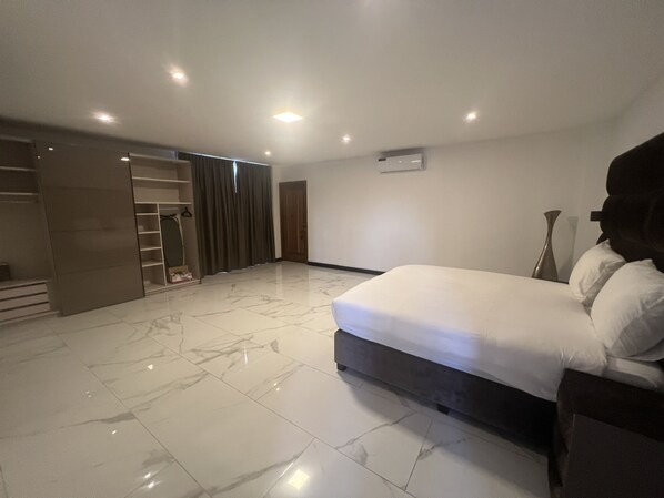 A modern bedroom with a large bed, a walk-in closet, and a bathroom.