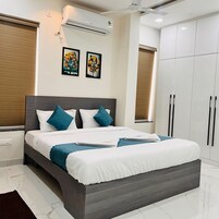 A modern bedroom with a large bed, a wardrobe, and an air conditioning unit.
