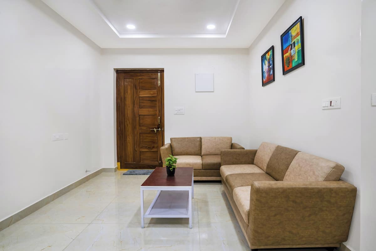 A living room with a brown sectional sofa, a white coffee table with a plant, and a wooden door.