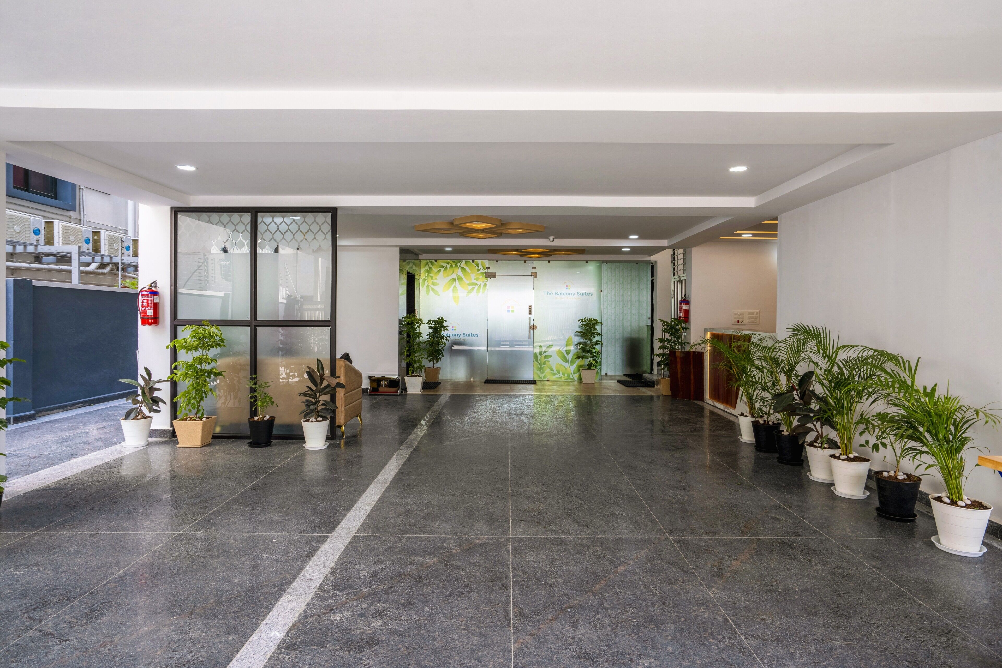 A spacious lobby with a modern design, featuring a reception desk, potted plants, and a clear view of the entrance.