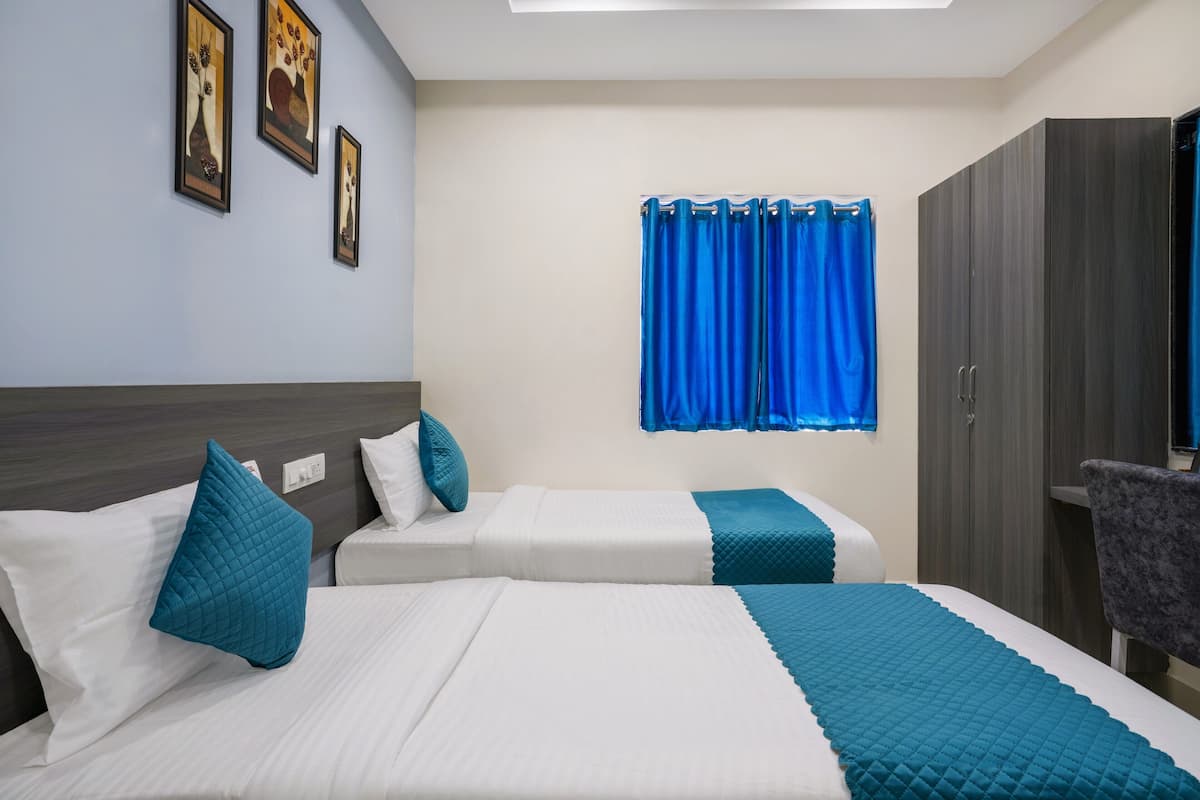 A hotel room with two beds, a wardrobe, and a window with blue curtains.
